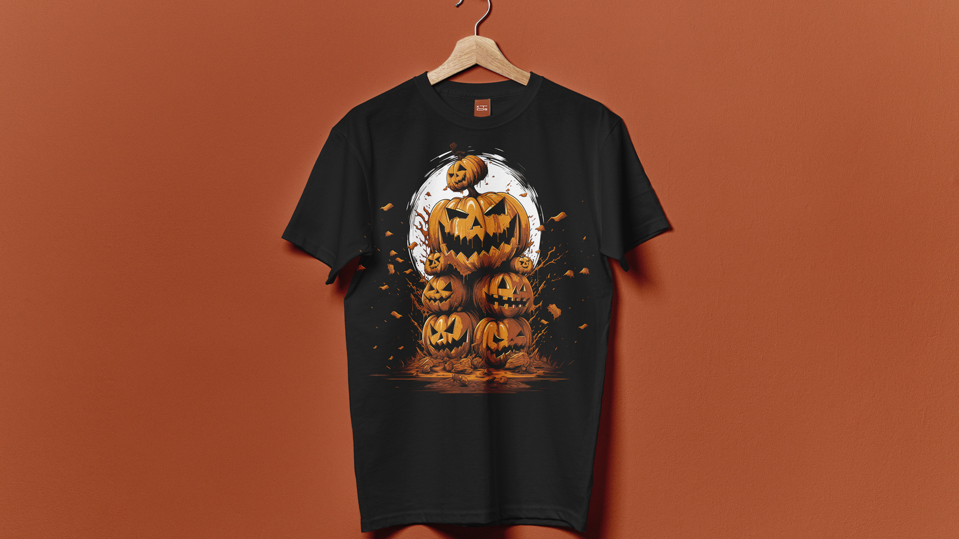 A black t-shirt hanging on a wooden hanger against a burnt orange background. The t-shirt showcases a detailed graphic of stacked jack-o'-lanterns in varying sizes. The largest pumpkin at the center features a menacing grin, with smaller pumpkins surrounding it. Behind the central pumpkin is a white, moon-like circle, creating a striking contrast. Flying leaves and dynamic brush strokes envelop the pumpkins, adding a sense of motion and autumnal atmosphere to the design.